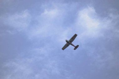 Bulutlu mavi gökyüzünün altında uçan bir uçağın dikey görüntüsü.