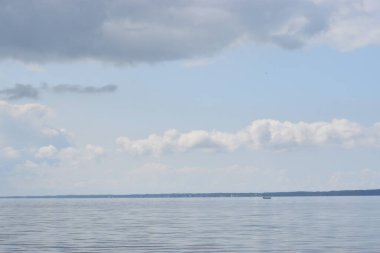 Bir iskeleden Baltık Denizi Körfezi manzarası. Ufuk çizgisi suyun üzerindeki bulutlar, sakin deniz yüzeyi ve atmosferik doğal ışık..