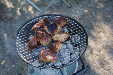 Izgarada ızgara yapan sulu et. Duman ve alevler iştah açıcı bir sahne yaratıyor.
