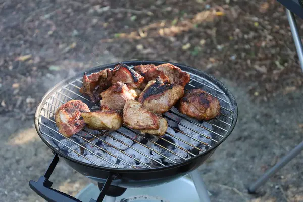 Izgarada ızgara yapan sulu et. Duman ve alevler iştah açıcı bir sahne yaratıyor.