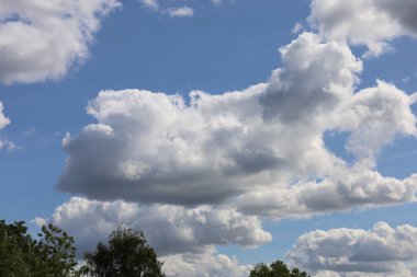 Fotoğraf mavi gökyüzündeki büyük bulutları gösteriyor. Görüntü bulutların hacmini ve şeklini ve gökyüzünün parlaklığını vurgular..