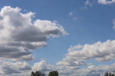 Fotoğraf mavi gökyüzündeki büyük bulutları gösteriyor. Görüntü bulutların hacmini ve şeklini ve gökyüzünün parlaklığını vurgular..
