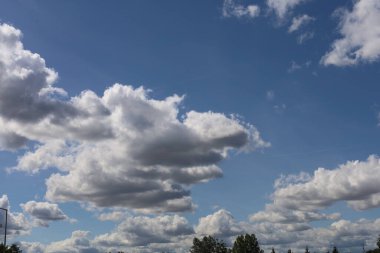 Fotoğraf mavi gökyüzündeki büyük bulutları gösteriyor. Görüntü bulutların hacmini ve şeklini ve gökyüzünün parlaklığını vurgular..