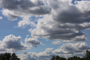 Fotoğraf mavi gökyüzündeki büyük bulutları gösteriyor. Görüntü bulutların hacmini ve şeklini ve gökyüzünün parlaklığını vurgular..