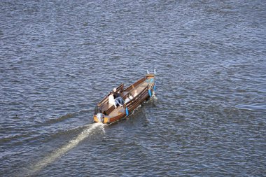 Motorboat moving along the Vistula River, creating waves and capturing dynamic water motion, travel, leisure, and river scenery in a natural landscape.
