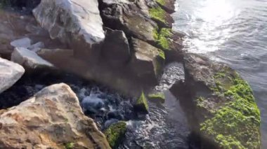 Kayaların arasından denize akan temiz su. Doğa ve deniz manzarası