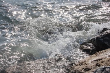 Renkli bir sonbahar gününde hafif rüzgarın esintisiyle canlanan güneş gökyüzünde parlıyor ve denizin dalgalı yüzeyi büyüleyici bir manzara sunuyor. Sakin bir sonbahar gününde dalgalı deniz manzarası. Dalgalı Deniz Burnu Güneşli Gökyüzünün Altında .