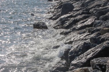 Renkli bir sonbahar gününde hafif rüzgarın esintisiyle canlanan güneş gökyüzünde parlıyor ve denizin dalgalı yüzeyi büyüleyici bir manzara sunuyor. Sakin bir sonbahar gününde dalgalı deniz manzarası. Dalgalı Deniz Burnu Güneşli Gökyüzünün Altında .