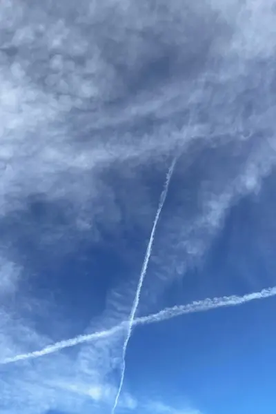 Blue sky with white clouds and contrails. Abstract background for design.Airplane trail in the blue sky with white cloudsbe used as background.Clear blue sky with white clouds and contrail trail. Panoramic image.
