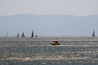 İstanbul, Türkiye. 17 Ağustos 2024 Fenerbahçe Shore 'da yelkenliler. Bu puslu ve sisli Ağustos gününde, Istanbuls Fenerbahçe kıyı şeridi açıklarındaki Marmara Denizi' nin parıldayan sularında yelkenliler süzülüyor. Marmara denizi. İstanbul İli.