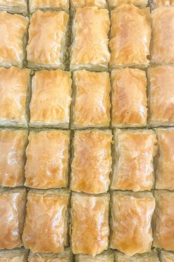 Lezzetli Pistachio Baklava - Geleneksel Tatlı. Altın çıtır tabakaları ve parlak şurubuyla vurgulanıyor, özenle hazırlanmış bir şam fıstığı baklavası var. Şam fıstığıyla doldurulmuş pekmezli Türk tatlısı..