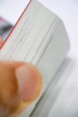 Kitap Sayfalarının Ayrıntılı Görünümü. Kalın bir kitabın sayfalarını kavrayan birinin parmaklarının yakın çekimini gösterir. Sayfaların dokusu ve kenarları, yüzeysel alan derinliği sayesinde açıkça vurgulanmıştır.. 