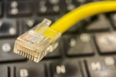 Ethernet Kablo Yakın plan. Ethernet kablo bağlayıcısının yakın plan fotoğrafı. İçerideki sekiz renkli kabloyu gösteriyor. Kablo sarı ve dizüstü bilgisayarın üzerine yerleştirilmiş..