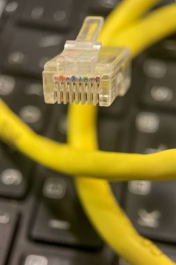 Ethernet Kablo Yakın plan. Ethernet kablo bağlayıcısının yakın plan fotoğrafı. İçerideki sekiz renkli kabloyu gösteriyor. Kablo sarı ve dizüstü bilgisayarın üzerine yerleştirilmiş..