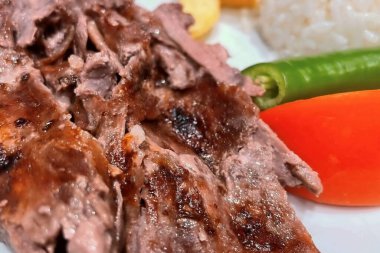 Sebzeli Lezzetli Doner Kebabı. Taze sebzelerle servis edilen sulu ve yumuşak donör kebabının ağız sulandırıcı yakın çekimi. Görüntü, ızgara etin zengin dokusunu ve iştah açıcı görünümünü ön plana çıkarıyor..