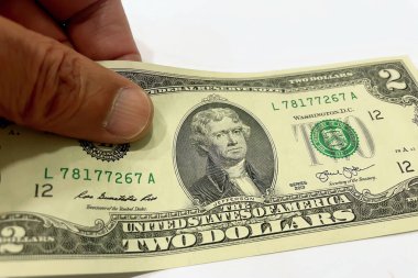 İki Dolarlık banknotun el ele tutuşması. İki dolarlık banknotu tutan bir elin detaylı bir görüntüsü. Tasarım özelliklerini vurguluyor.. 