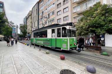 Kadıköy, İstanbul, Türkiye. 25 Mayıs 2025. Kadıköy, İstanbulya 'da tarihi Moda Tramvayı. İstanbul' un Kadıköy kentindeki büyüleyici Moda Tramvay hattı üzerinde, canlı şehir yaşamı ve tarihi kent manzarası ile çevrili, antika bir yeşil tramvay sürüyor..