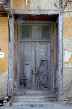 Evin duvarındaki eski ahşap kapı. Kavramsal görüntü. Eski Ev Duvarındaki Tahta Kapı. Mimari Detaylar Zamanla Aşındı ve Yıprandı. Solmuş duvar boyası, zamanın ve terk edilmenin etkilerini gösterir.. 