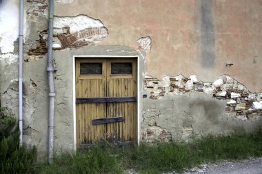 Evin duvarındaki eski ahşap kapı. Kavramsal görüntü. Eski Ev Duvarındaki Tahta Kapı. Mimari Detaylar Zamanla Aşındı ve Yıprandı. Solmuş duvar boyası, zamanın ve terk edilmenin etkilerini gösterir.. 