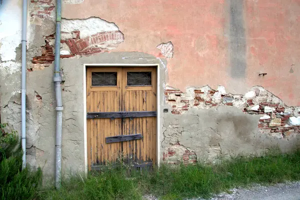 Evin duvarındaki eski ahşap kapı. Kavramsal görüntü. Eski Ev Duvarındaki Tahta Kapı. Mimari Detaylar Zamanla Aşındı ve Yıprandı. Solmuş duvar boyası, zamanın ve terk edilmenin etkilerini gösterir.. 