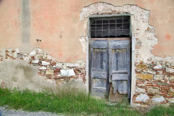 Evin duvarındaki eski ahşap kapı. Kavramsal görüntü. Eski Ev Duvarındaki Tahta Kapı. Mimari Detaylar Zamanla Aşındı ve Yıprandı. Solmuş duvar boyası, zamanın ve terk edilmenin etkilerini gösterir.. 