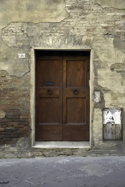 Evin duvarındaki eski ahşap kapı. Kavramsal görüntü. Eski Ev Duvarındaki Tahta Kapı. Mimari Detaylar Zamanla Aşındı ve Yıprandı. Solmuş duvar boyası, zamanın ve terk edilmenin etkilerini gösterir.. 