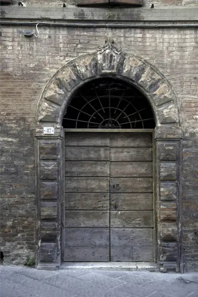 Evin duvarındaki eski ahşap kapı. Kavramsal görüntü. Eski Ev Duvarındaki Tahta Kapı. Mimari Detaylar Zamanla Aşındı ve Yıprandı. Solmuş duvar boyası, zamanın ve terk edilmenin etkilerini gösterir.. 