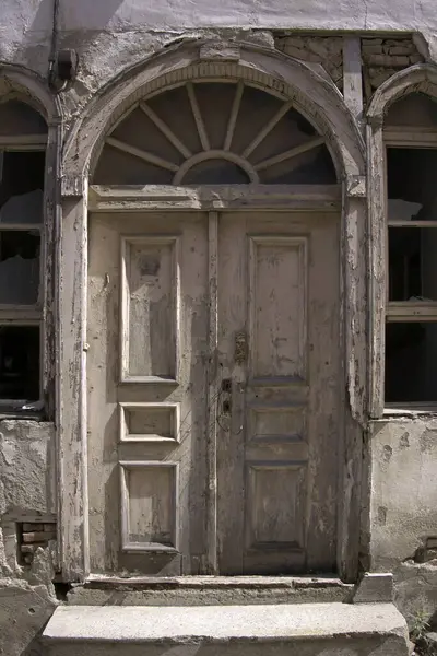 Evin duvarındaki eski ahşap kapı. Kavramsal görüntü. Eski Ev Duvarındaki Tahta Kapı. Mimari Detaylar Zamanla Aşındı ve Yıprandı. Solmuş duvar boyası, zamanın ve terk edilmenin etkilerini gösterir.. 
