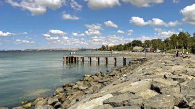 İstanbul, Türkiye. 22 Haziran 2025. İstanbul 'da kıyı yürüyüşü, parçalı bulutlu bir gökyüzünün altındaki sakin denizin yanındaki kayalık kıyı şeridi ile İstanbul' un Florya kıyısında güneşli bir gün. Sahne, bu popüler kıyı bölgesinin sakin atmosferini yakalıyor..