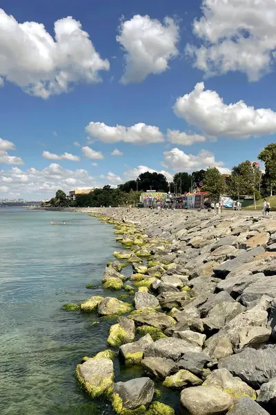 İstanbul, Türkiye. 22 Haziran 2025. İstanbul 'da kıyı yürüyüşü, parçalı bulutlu bir gökyüzünün altındaki sakin denizin yanındaki kayalık kıyı şeridi ile İstanbul' un Florya kıyısında güneşli bir gün. Sahne, bu popüler kıyı bölgesinin sakin atmosferini yakalıyor..