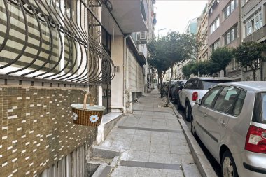 İstanbul, Türkiye. 2 Temmuz 2025. Sisli, İstanbul 'da sabah. Dar bir caddede üst kattan dekoratif bir sepet sarkıyor..