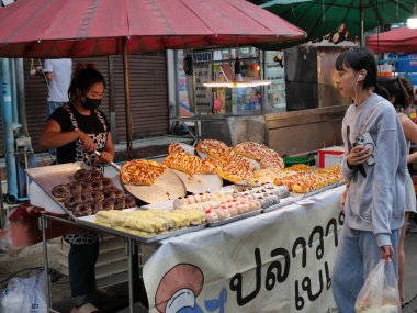 Tayland, Bangkok, Chok Chai 4 Taze Pazar 13 Mayıs 2025 akşamı. Sıradan insanlar akşam yemeği için kızarmış böcekler, pizza ve diğer yiyecekleri alıyorlar..