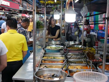Tayland, Bangkok, Chok Chai 4 Taze Pazar 13 Mayıs 2025 akşamı. Sıradan insanlar akşam yemeği için kızarmış böcekler, pizza ve diğer yiyecekleri alıyorlar..