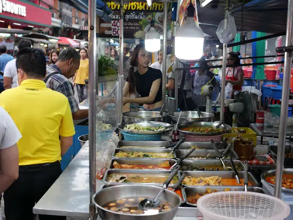 Tayland, Bangkok, Chok Chai 4 Taze Pazar 13 Mayıs 2025 akşamı. Sıradan insanlar akşam yemeği için kızarmış böcekler, pizza ve diğer yiyecekleri alıyorlar..