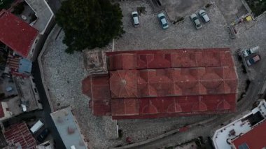 Günbatımında Lefkara köyünün insansız hava aracı görüntüleri, renkli bir gökyüzüne karşı, yuvarlanan tepeler arasında kırmızı çatılı, dağ siluetleri olan beyaz evler gösteriyor. Tarihi mimari harmanlamayı içerir