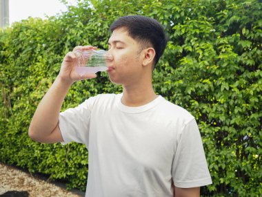 Genç adam plastik şişeden su içiyor.