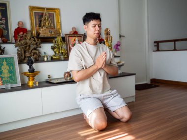 Genç adam elinde tütsü çubukları tutuyor bacak bacak üstüne atıyor, evde ruhani sabah rutini uyguluyor.