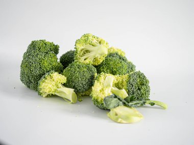 Stüdyo ışığı altında sade yüzeylere saçılmış doğranmış brokoli çiçeklerinin yakın çekimi, tazeliği, bitkisel beslenmeyi ve salata, yemek pişirme, vegan menüsü veya sağlık hizmetleri için aşçılık ilhamını vurguluyor 