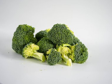 Temiz beyaz arkaplana yerleştirilmiş taze brokoli parçaları, gıcır gıcır dokuyu, organik şekli ve vegan, detoks veya besin odaklı içerik ve sağlıklı yaşam tarzı için ideal yeşil rengi vurguluyor. 