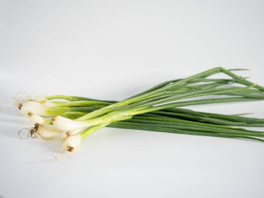 Taze soğanlar gevşek bir şekilde beyaz arka planda sergileniyor. Tazelik ve yeşillik ve beyazların kontrastı. Bileşimi yiyecek, bitki veya organik içerik için temiz, minimal ve idealdir.