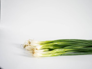 Parlak yeşil yapraklı bir avuç yeşil soğan ve beyaz arka planda duran temiz beyaz ampuller. Bileşimi yiyecek, bitki veya organik içerik için temiz, minimal ve idealdir.