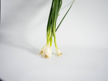 Beyaz arka planda, yumuşak doğal gölgeler ve net organik detaylarla izole edilmiş bir avuç yeşil soğan. Bileşimi yiyecek, bitki veya organik içerik için temiz, minimal ve idealdir.