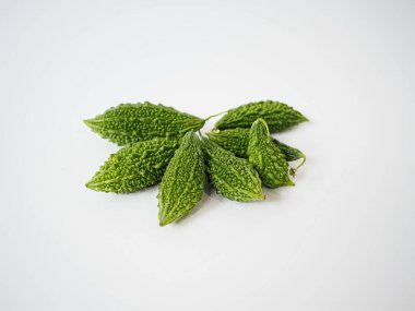 Bitkisel tazeliği, yerel Tayland sebze temaları veya temiz malzeme görsellerini temsil etmek için beyaz düz yüzeyde düzenlenmiş acı kavun yaprakları kümesi.