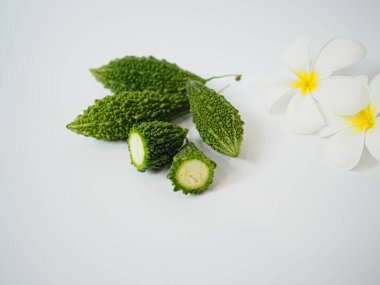 Yaprak ve çiçek desenli acı kavun parçaları organik gıda, detoks ürünleri veya bitkisel markalaşma için tazeliği iletmek amacıyla minimalist beyaz ayar üzerinde fotoğraflandı