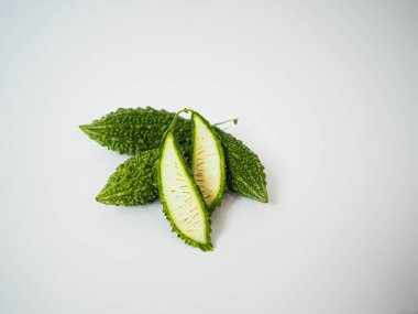 Acı kavun parçalarının ikilisi beyaz arka planda tepeden tırnağa çekildi. Temiz kesit ve parlak yeşil renk malzeme ışıkları için ideal.