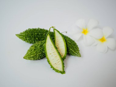 Sağlıklı gıda tasarımında ya da Tayland bitkisel rehberlerinde kullanmak üzere temiz stüdyo zemininde tropikal çiçek elementinin yanında çapraz kavun kesiti görüntüsü