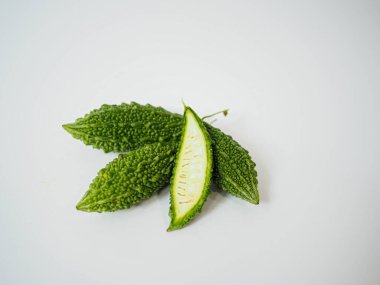 Yumuşak eğimli kesilmiş bitkisel acı kavun parçaları ve sağlıklı besin veya tıbbi görsel rehberler için beyaz üzerine düzgün bir düzen içinde yakalanmış tohum kümesi.