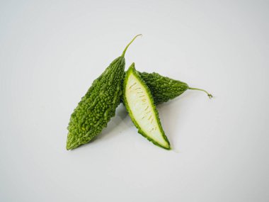 Besin bilimini veya Asya bitki kaynakları medyasını geliştirmek için beyaz zemin üzerinde görülebilir çekirdek çekirdekli organik acı kavun parçaları ve taze doku