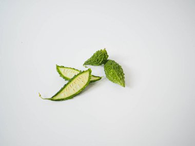 Acı kavun beyaz arka planda yumuşak gölgelerle kesilmiş ve dümdüz yatıyordu. Yüzeyi ve iç deseni vurgular