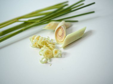 Üç limon otu sapı merkezde gösterilen birkaç kesik merminin arkasında kesişiyor. Yumuşak stüdyo ışığı ile sunulan beyaz arka plan baharat paketleme veya tarif görselleri için idealdir.